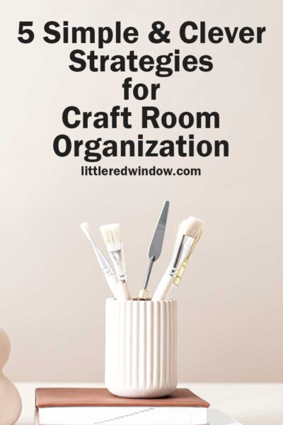 what paintbrushes and art tools in a white jar on top of a tan book