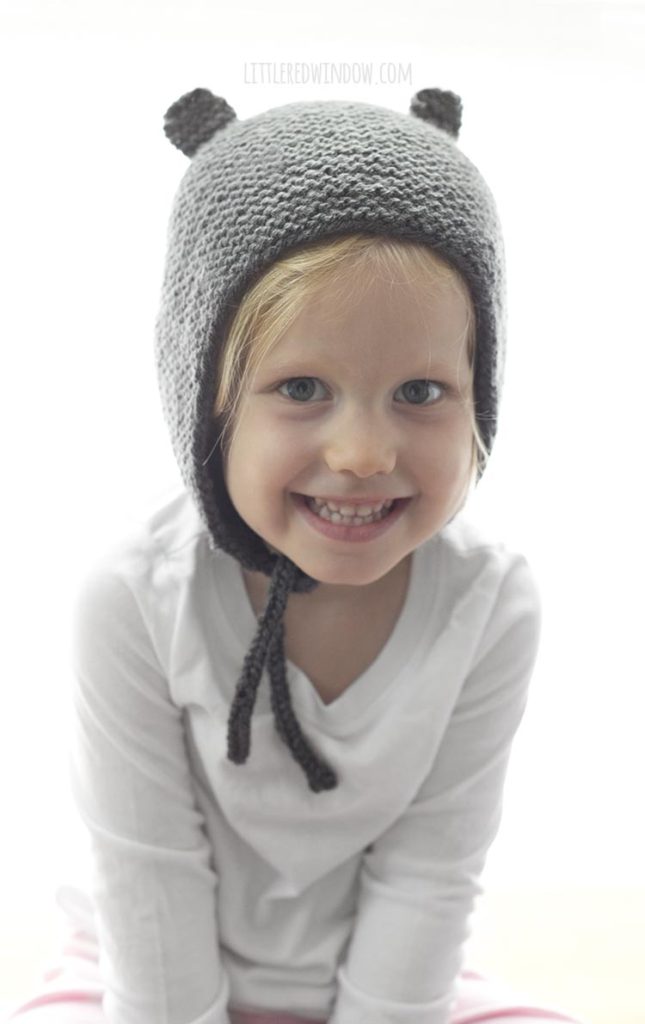 Smiling little girl wearing a gray knit bonnet with bear ears