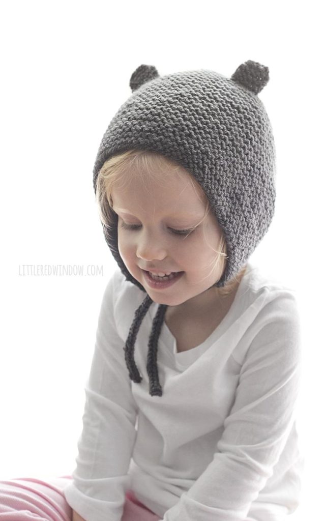 little girl looking down and wearing gray knit bonnet with bear ears