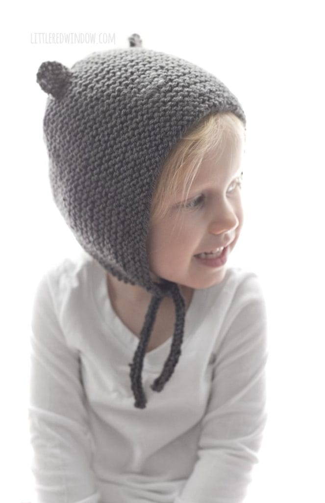 little girl wearing bear ear knit bonet and looking off to the right