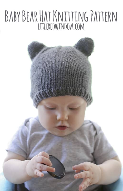 Baby holding a lens cap and wearing a knit hat with bear ears