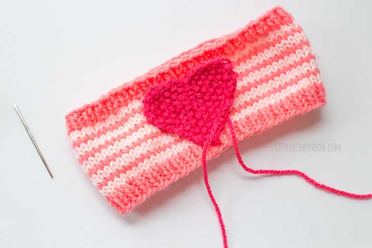 image showing where to place and sew the knit heart shape on the striped knit headband with a yarn needle