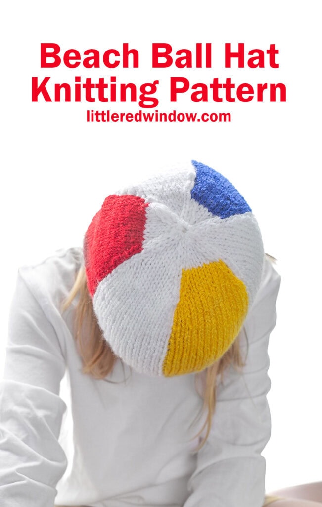 child in white shirt leaning way forward to show the top of a knit beach ball hat