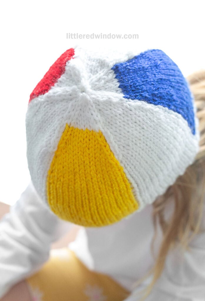 closeup of the top of a beach ball hat knit in white with red blue and yellow sections