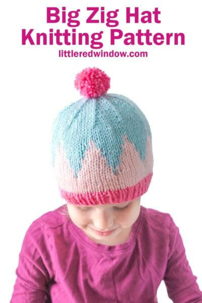 Young child wearing the Big Zig Hat, featuring a pink brim, blue and white zigzag pattern, and a pink pom-pom. Text above reads: "Big Zig Hat Knitting Pattern littleredwindow.com".