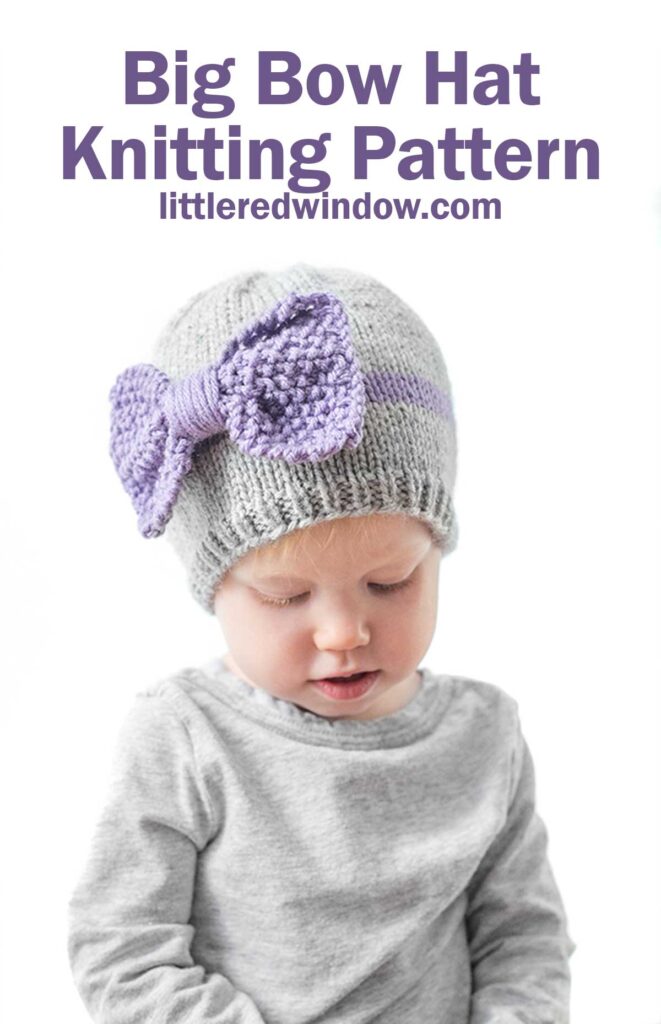 child wearing a gray shirt and gray knit hat with a purple band around the middle a large purple seed stitch bow on the front looking down at their lap in front of a white background