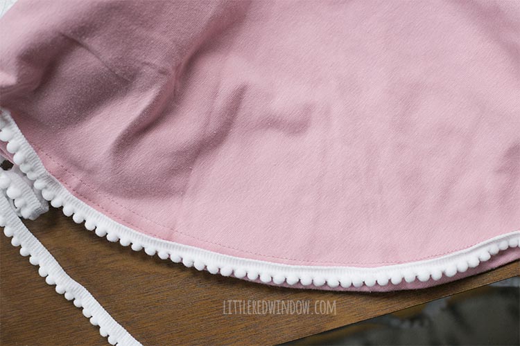pink dress with white pom pom trim laid around the bottom hem