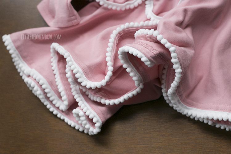 bottom of pink dress with all of the white pom pom trim sewn on