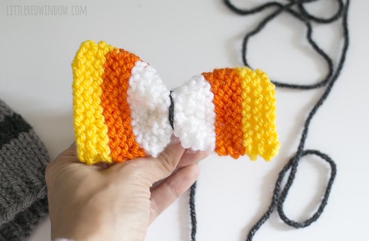 Hand pinching the knit bow in the middle to form a bow shape