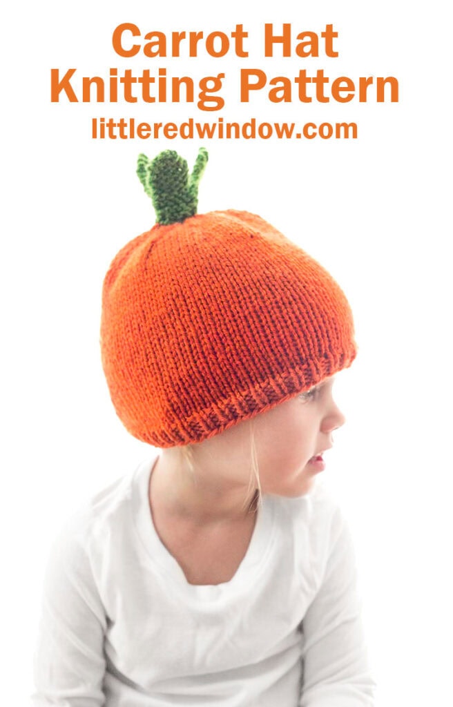 child in white shirt wearing an orange knit carrot hat with green knit carrot leaves on top looking off to the right