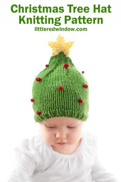 A baby adorably sports a green Christmas tree hat, complete with red bobbles and a yellow star atop, set against a crisp white backdrop. Above reads "Christmas Tree Hat Knitting Pattern," accompanied by a website URL.