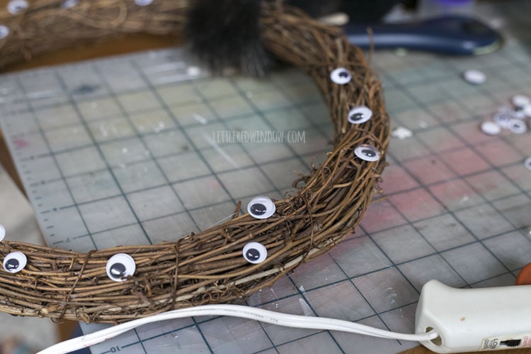 closeup of grapevine wreath with googly eyes being glued into it