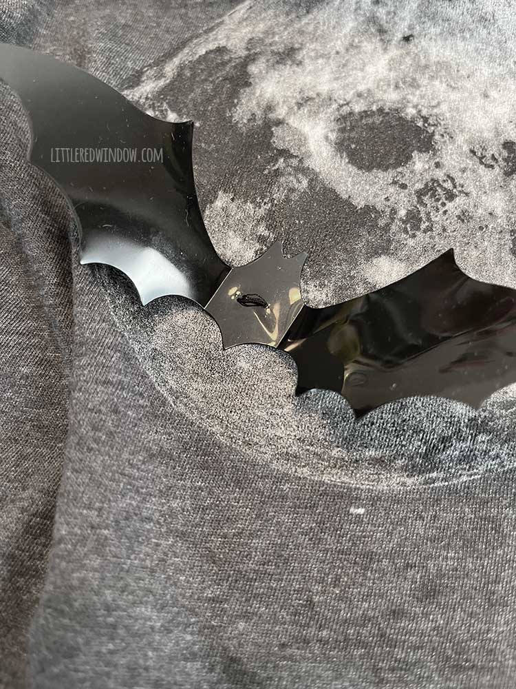 black plastic bat silhouette sewn to the front of the moon tshirt like a button