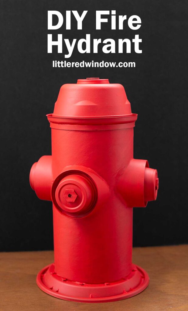 A red DIY fire hydrant made from recycled materials, set against a black background. The text above reads