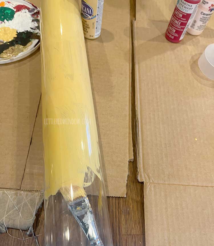 in process image of a large clear plastic tube being painted inside with a coat of yellow acrylic paint