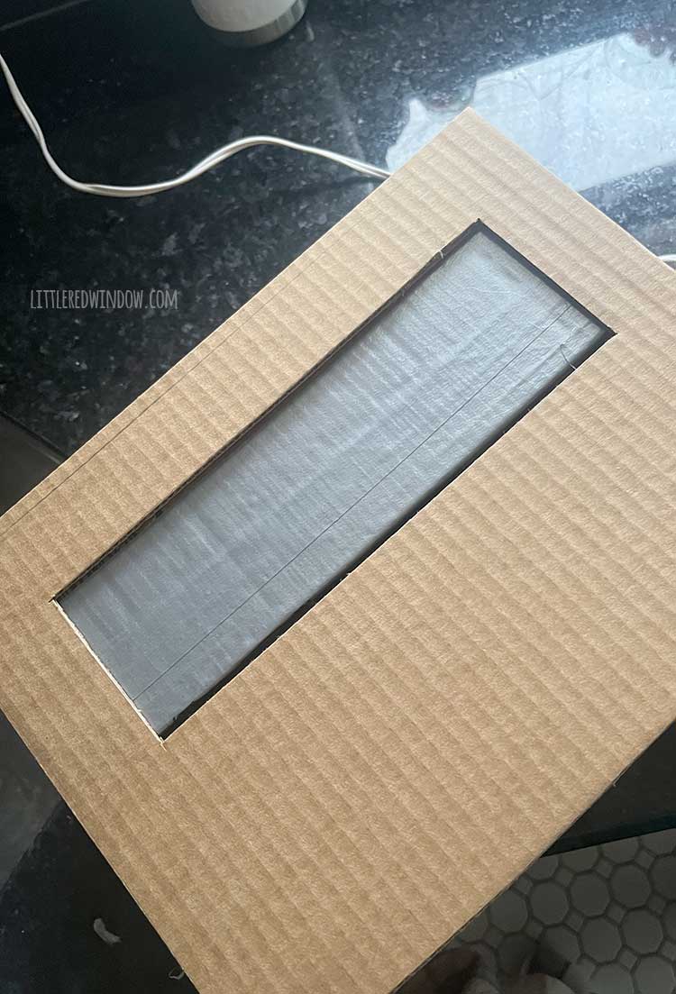 image of cardboard box with silver duct tape behind the pencil sharpener opening