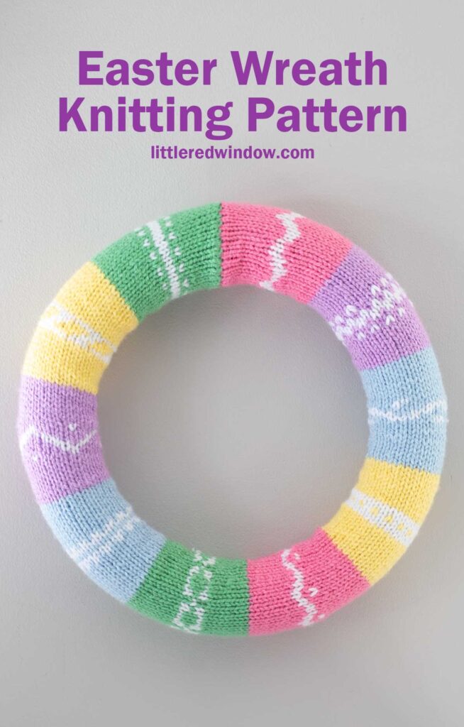 Colorful knitted Easter wreath with sections in pastel shades of green, pink, purple, blue, and yellow, each with white patterns. Text at the top reads