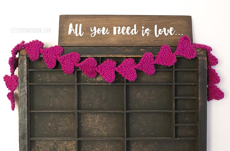 Easy knit heart garland strung over an old printer's tray