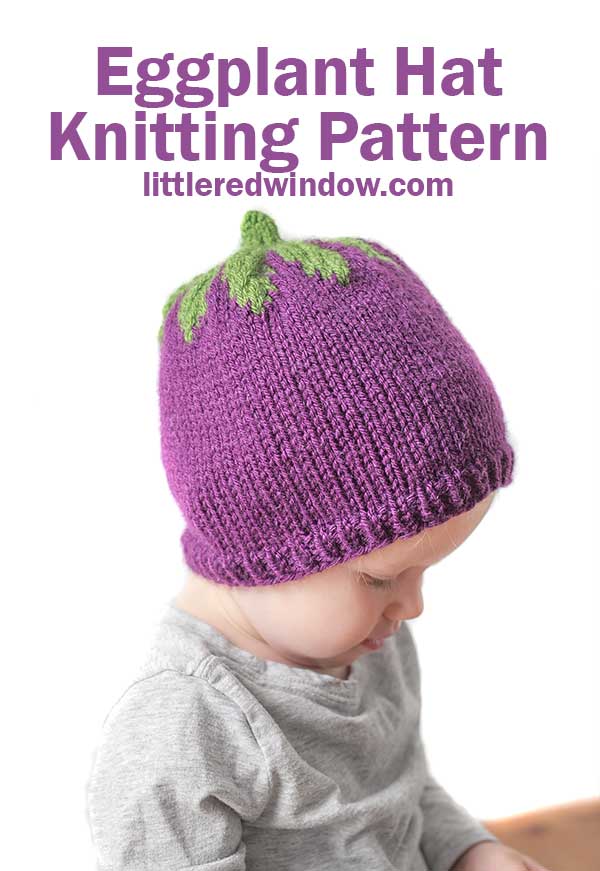 left side view of baby in gray shirt wearing a purple knit hat with green leaves on top that looks like an eggplant in front of a white background