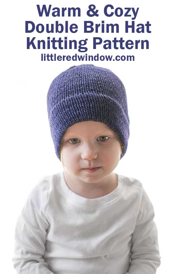 child in white shirt wearing a dark navy blue knit hat in front of a white background