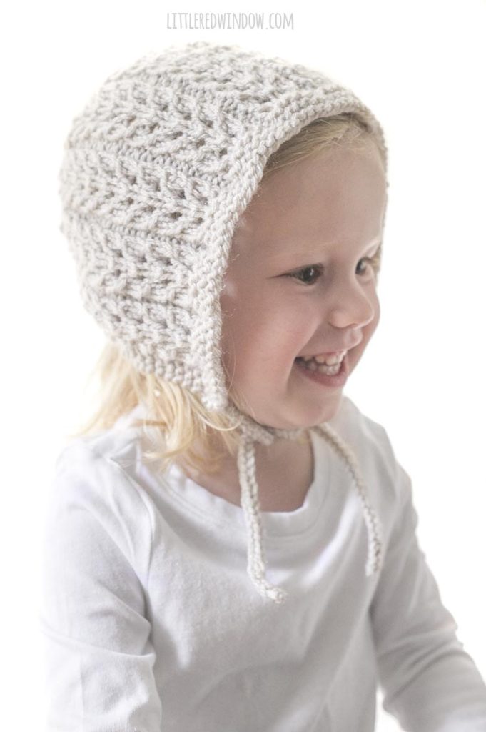 smiling toddler wearing tan colored flutter lace bonnet