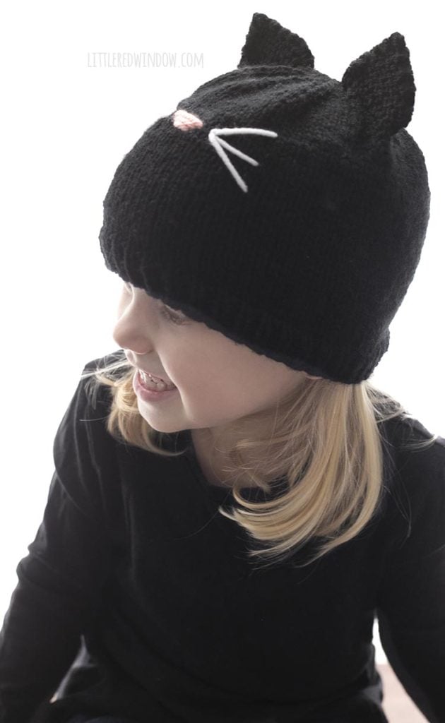 side view of little girl wearing black cat hat and looking off to the left