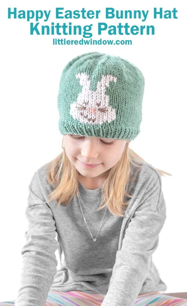 A young girl dons a green Easter bunny hat with a charming white bunny design, looking down in her cozy gray sweater. The text above says,
