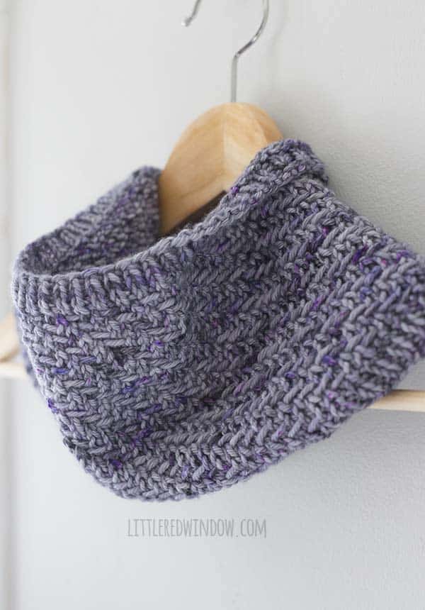 closeup of neckline of hazel herringbone cowl hanging on a wood hanger