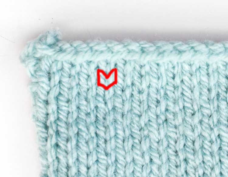 closeup of stockinette stitch swatch in light blue with one single knit stitch outlines in red