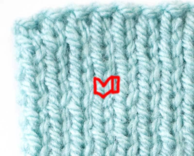 closeup of 1 by 1 ribbing with a single knit stitch and a single purl stitch outlined in red