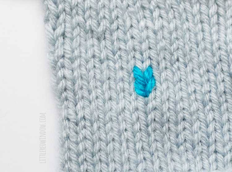 two electric blue duplicate stitches one above the other on a field of light blue stockinette stitch knitting