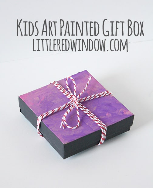 gift box with pink and purple swirly painted lid tied with red baker's twine bow