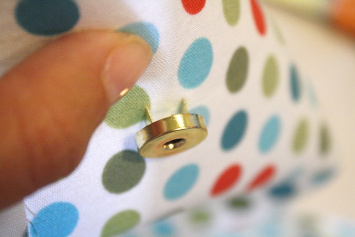 person inserting a metal snap through fabric