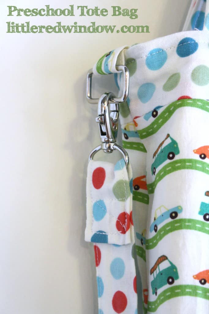 Closeup of Handmade tote back with red and blue and green car and bus fabric in front of a white wall