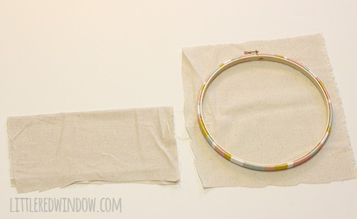 Hoop laying on a square of fabric with another folded piece for the pocket next to it