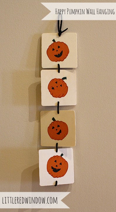 4 wooden squares with cute jack o lantern faces painted on them, hanging vertically