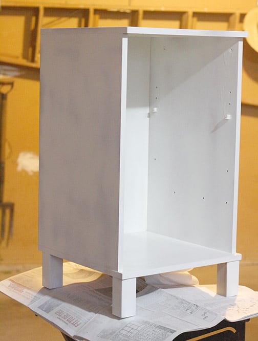 Nightstand with shelves and drawer removed and one coat of white paint on it.