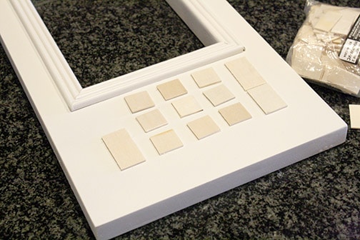 Small squares of wood laid out on the microwave door to show where buttons go