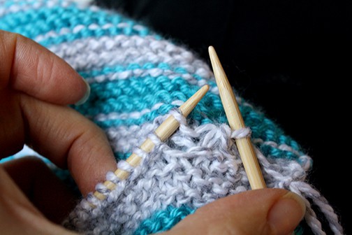 Photo showing how to left needle to pick up a stitch from the body of the scarf