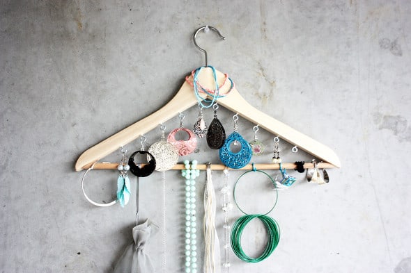 A wooden hanger with small hooks added to hold jewelry
