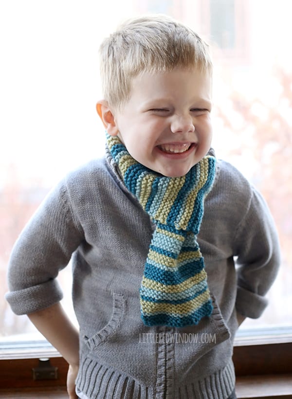Smiling boy wearing gray sweater and green and blue striped scarf