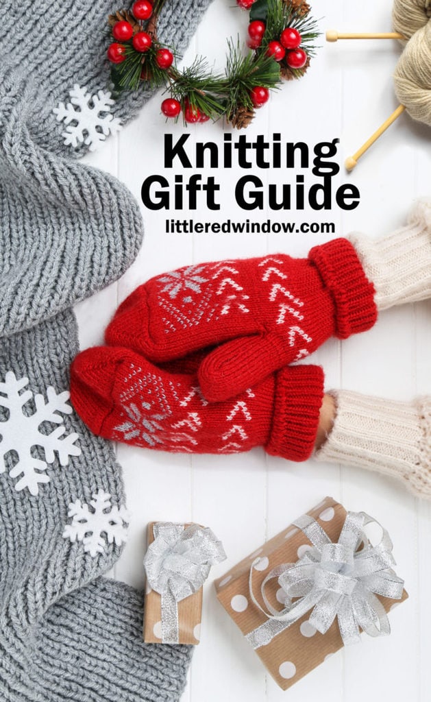 Hands in knitted mittens with grey scarf, snowflakes and gift boxes on white wooden table