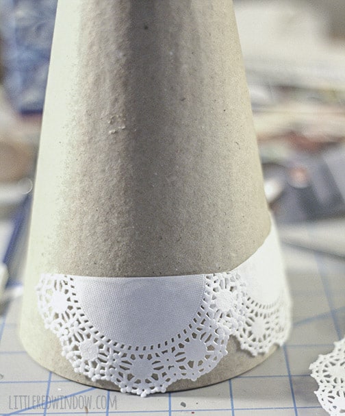Paper mache cone being covered with doilies