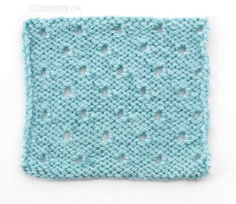 the wrong side of a light blue square swatch of basic eyelet stitch knitting on a white background