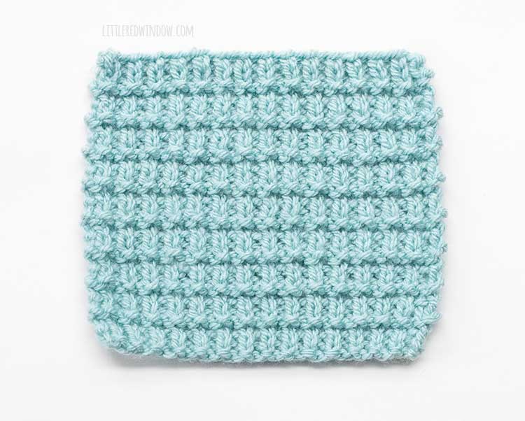 the wrong side of a light blue square swatch of broken rib stitch knitting on a white background