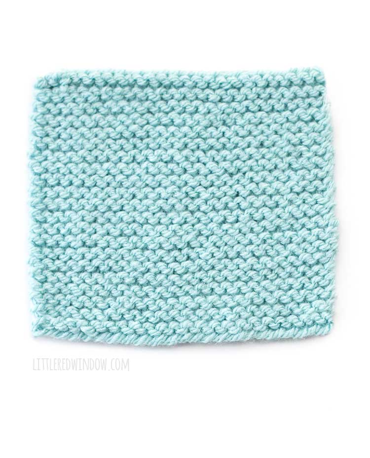 light blue square of garter stitch knitting showing the back wrong side of the fabric in front of a white background