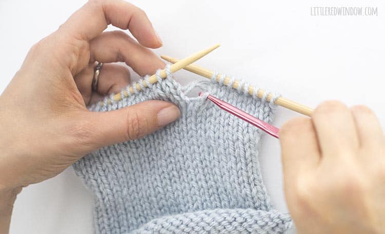 Grab the horizontal yarn behind the dropped knit stitch with your crochet hook