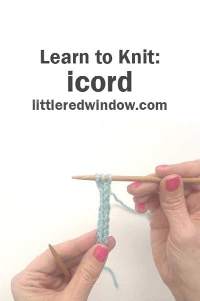 Two hands with pink nail polish hold wooden knitting needles, demonstrating how to knit an i-cord with light blue yarn. Text above reads: