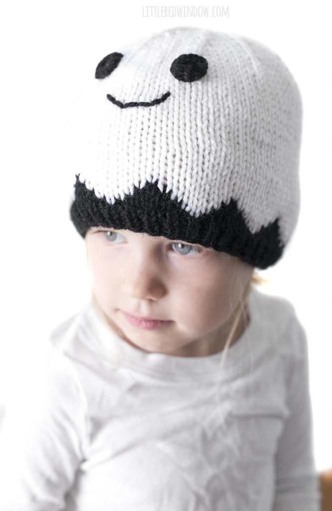 Little girl wearing a white smiling ghost hat and looking off to the left