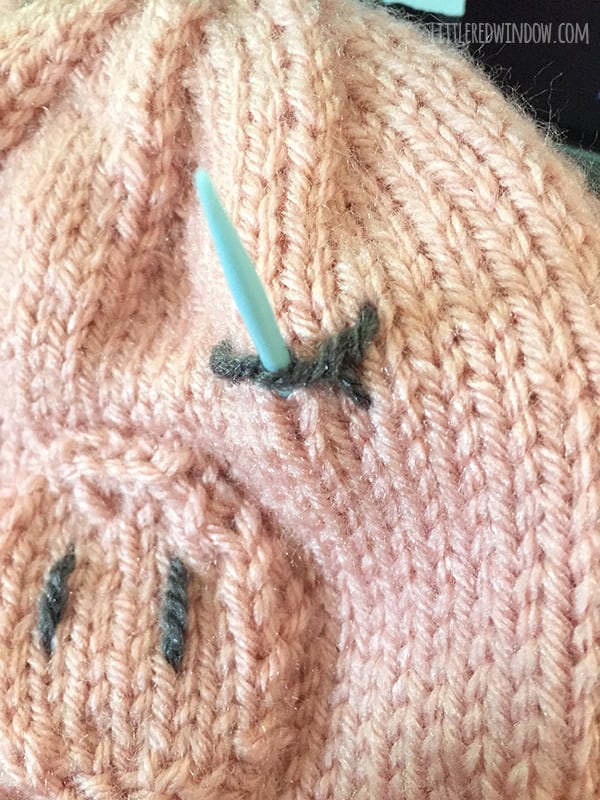 Pig hat eye with yarn needle finishing the stitch